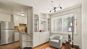 A modern kitchen with white cabinetry, a stainless steel refrigerator, and a wooden floor.