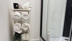 A bathroom with a white towel rack holding multiple towels, a bottle of hand soap, and a potted plant. - Madrid Dream House (Madrid)