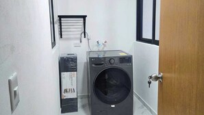 A compact laundry room with a washing machine, a dryer, and a small window. - Villa Leo Room with bunk bed ideal for families, in the heart of Cancun (Cancun)