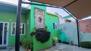 A green building with a lion head sculpture, potted plants, and a mural. - Villa Leo Room with bunk bed ideal for families, in the heart of Cancun (Cancun)