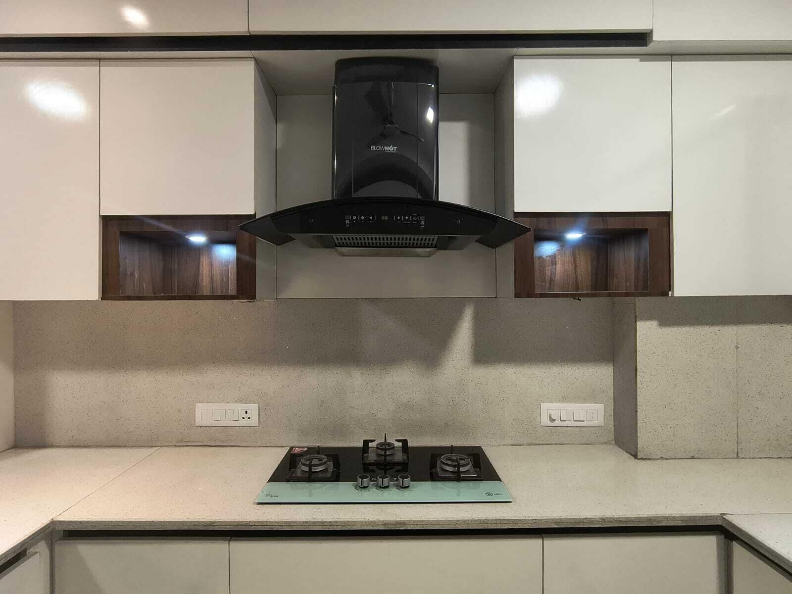 A kitchen with a gas stove, a black range hood, and white cabinets.