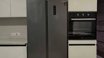 A modern kitchen with two stainless steel refrigerators, a built-in oven, and white cabinetry.