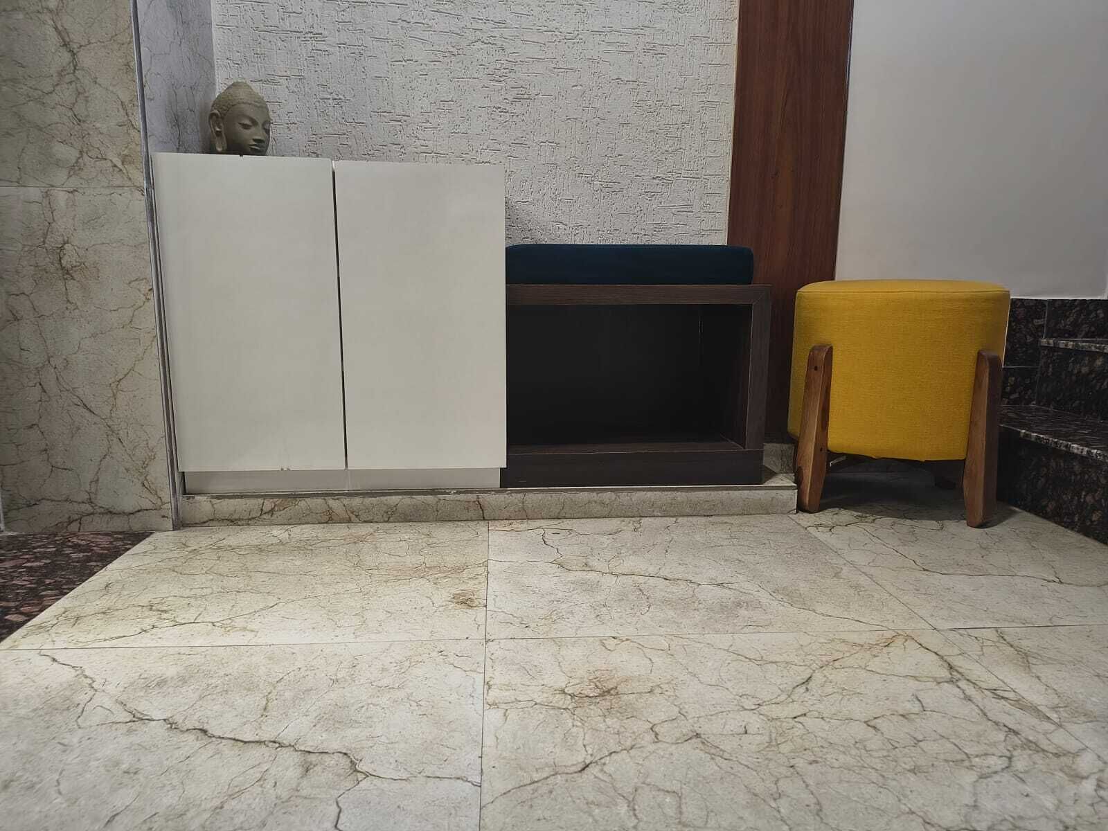 A corner with a white cabinet, a dark bench, and a yellow stool.