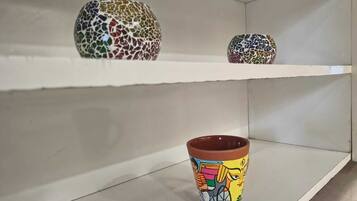 Una estantería con tres jarrones de cerámica y una taza pintada.