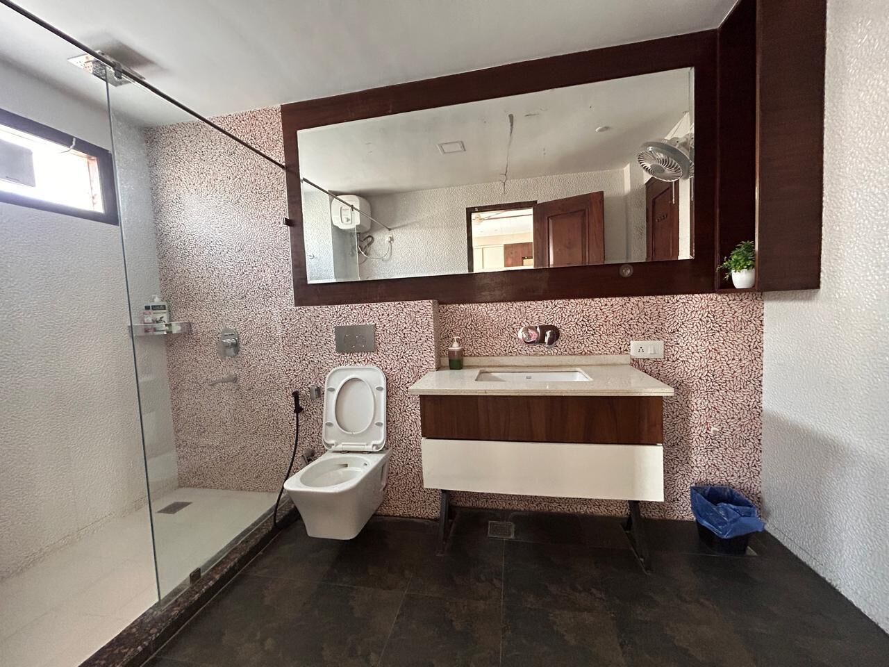 A modern bathroom with a glass shower enclosure, a white toilet, and a vanity with a mirror above.