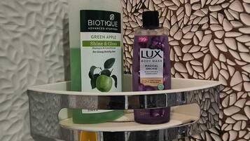 Uno scaffale in bagno con uno shampoo Biotique e un detergente corpo Lux.