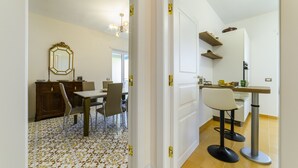 Una cocina moderna con comedor, que incluye una puerta blanca, un mueble de madera y piso de baldosas.