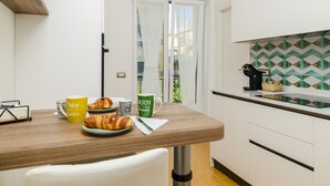 Una cocina con encimera de madera, una silla blanca y una puerta que da a un balcón.