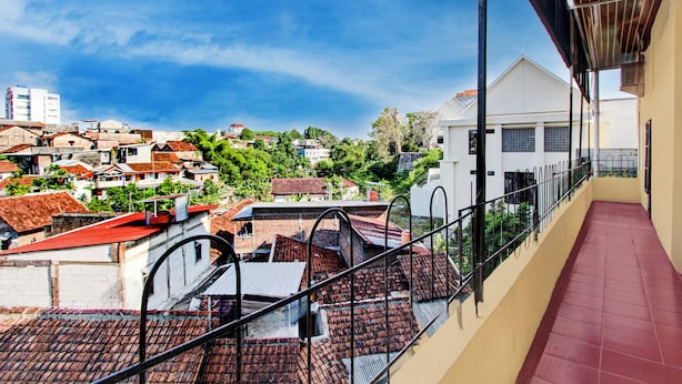 A balcony with a red-tiled floor and a view of a residential area with houses and greenery. - Hotel O Near Tugu Yogyakarta 2 formerly Monjali Inn (Sinduadi)