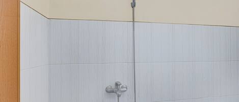 A shower with a handheld showerhead and a wall-mounted faucet.