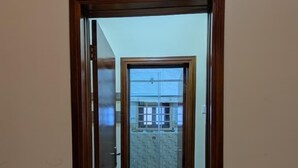 Corredor que dá acesso a um banheiro com vaso sanitário e área de chuveiro.