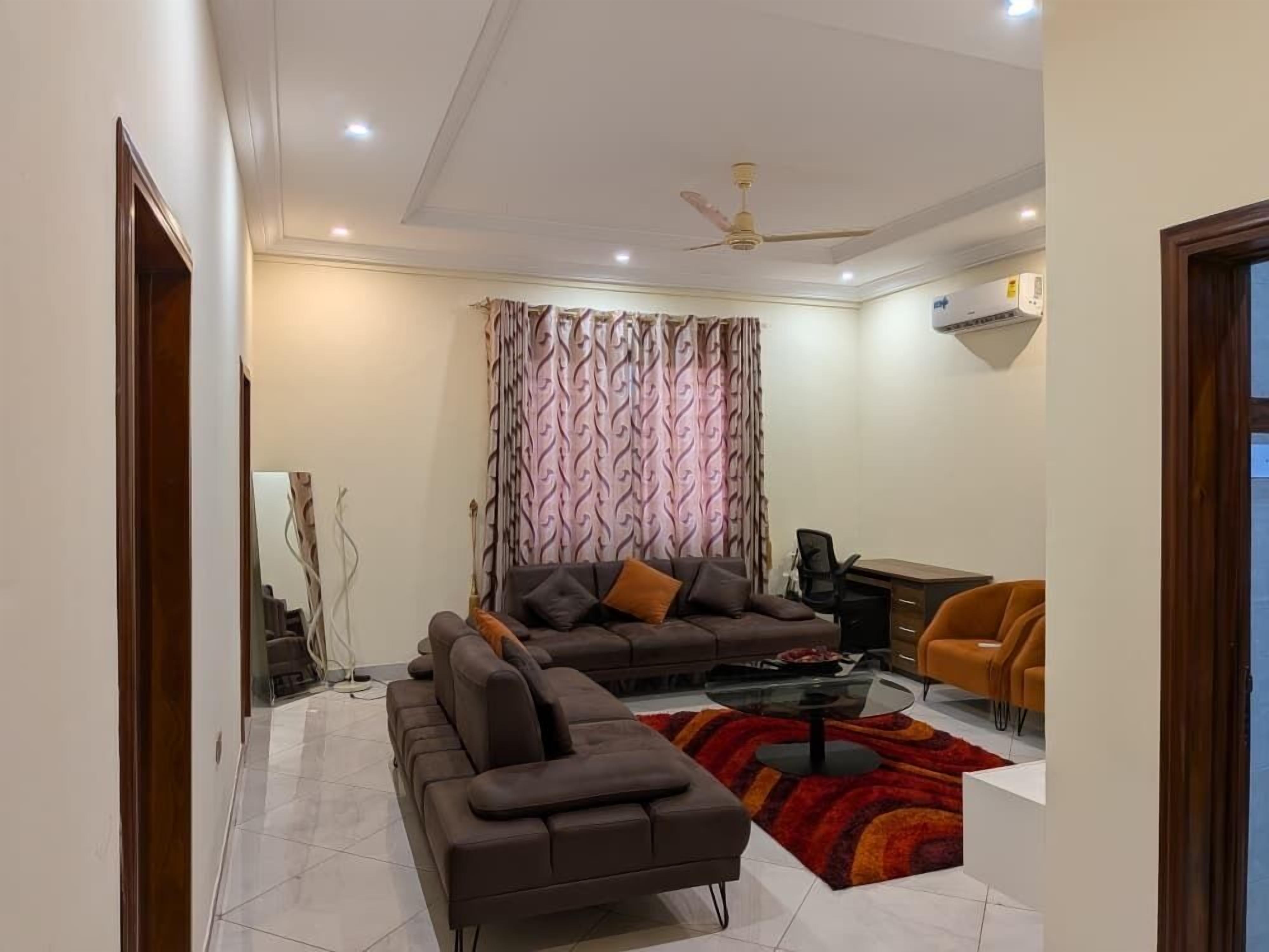 A modern living room with a sofa, armchairs, a coffee table, and a patterned curtain.