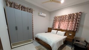 Quarto com cama, guarda-roupa e ventoinha no teto.