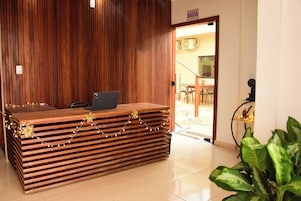 Una mesa de recepción con una computadora portátil, paneles de madera y un cartel que dice "SAÍDA".