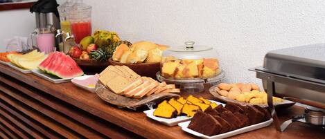 A buffet with various food items including fruits, pastries, and a cake.