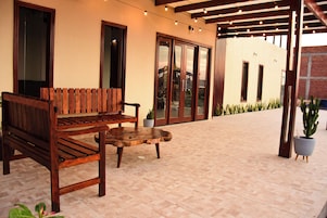 Un conjunto de banco y mesa de madera en un patio empedrado, con un edificio al fondo.