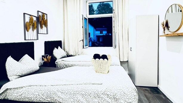 A bedroom with two beds, a window, a mirror, and a door. - Compact Studio Apartment with Essentials, Ideal for 2 Guests (Wien)