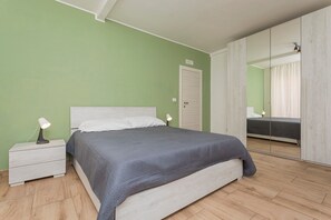 Un dormitorio con cama, mesita de noche, lámpara, armario y espejo.