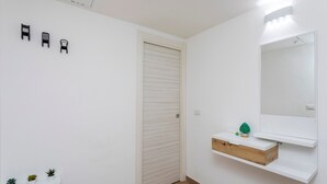 A room with a closed door, a mirror, a shelf with a plant, and three wall-mounted hooks. - 'Eleven Holidays Home' Apartment with Balcony, Wi-Fi and Air Conditioning (Catania)