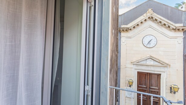 A building with a clock, a door, and a window. - 'Eleven Holidays Home' Apartment with Balcony, Wi-Fi and Air Conditioning (Catania)