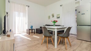 A modern living room with a dining table, chairs, a sofa, and a television. - 'Eleven Holidays Home' Apartment with Balcony, Wi-Fi and Air Conditioning (Catania)