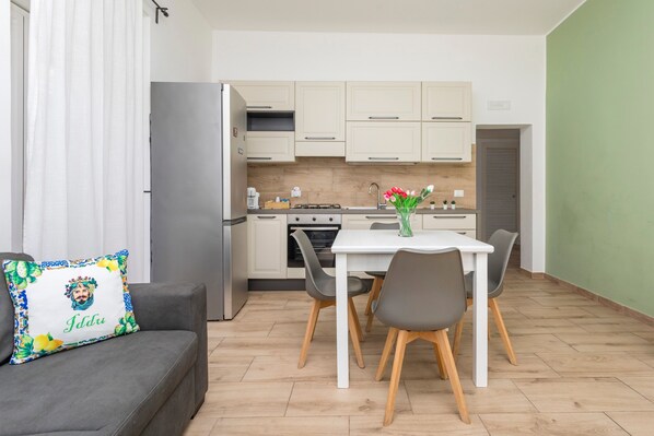 Una cocina moderna con armarios blancos, una mesa de comedor con sillas y un refrigerador.