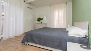 A bedroom with a bed, a bedside table, a mirror, and a potted plant. - 'Eleven Holidays Home' Apartment with Balcony, Wi-Fi and Air Conditioning (Catania)