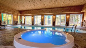 An indoor swimming pool with a stone floor, surrounded by wooden walls and large windows. - Domaine Rivière Sacacomie - La Mésange (Saint-Alexis-des-Monts)