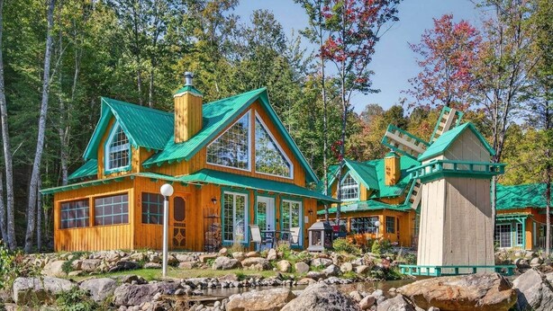 A wooden cabin with a green roof, a chimney, and a small porch area. - Domaine Rivière Sacacomie - La Mésange (Saint-Alexis-des-Monts)