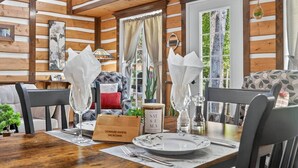 A wooden interior with a dining table set for two, featuring a sign reading "DOMAINE RIVIÈRE SACACOMIE". - Domaine Rivière Sacacomie - Le Pic-Bois (Saint-Alexis-des-Monts)