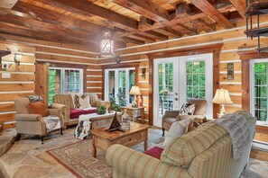 L’intérieur d’une cabane en rondins, avec une cheminée, plusieurs coins salon et de grandes fenêtres.