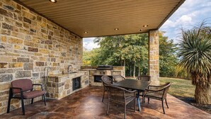 An outdoor patio with stone walls, a grill, and wicker furniture.