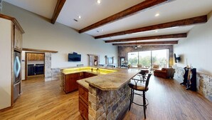 A spacious kitchen with a large island, wooden cabinets, and a stone accent wall.