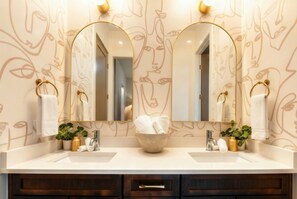 A bathroom with two sinks, a large mirror, and a towel rack. - Luxury Retreat Double Rooftop Deck Game Room (Nashville)