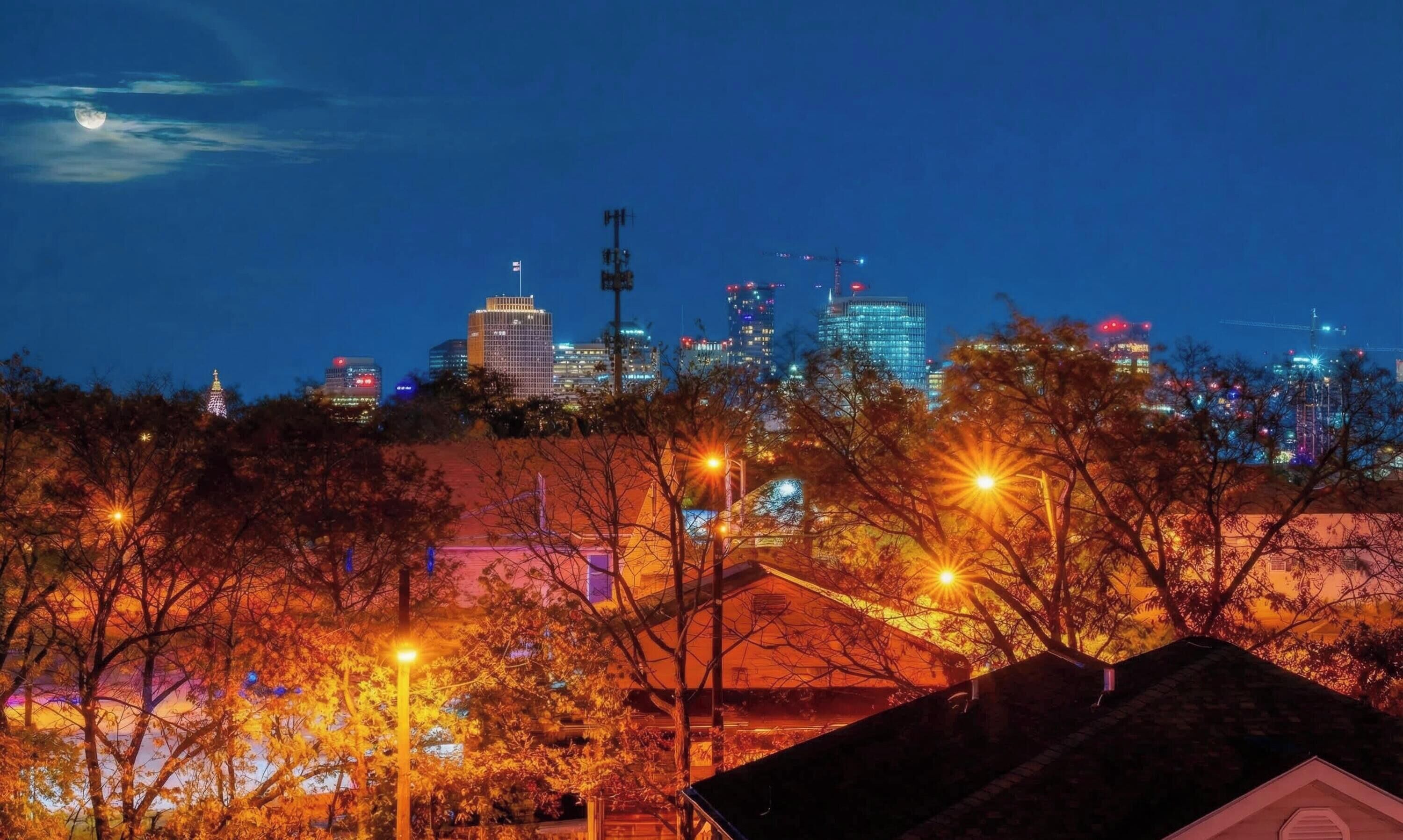 A nighttime cityscape with illuminated buildings and a clear sky.