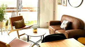 Ein modernes Wohnzimmer mit einem großen Fenster, einem braunen Ledersofa, einem Holztisch und einem Esstisch.