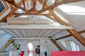 Ein Schlafzimmer im Loft-Stil mit schrägem Dach, Holzbalken, einem Etagenbett, einem Schreibtisch und einem Stuhl.