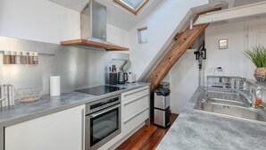 Una cocina moderna con horno empotrado, pileta de acero inoxidable y tragaluz.