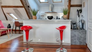Cocina moderna con una isla central, tragaluces y taburetes rojos.