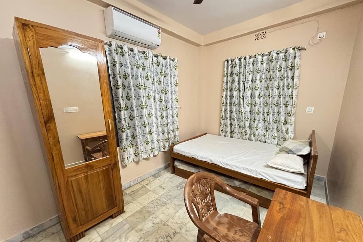 A bedroom with a wooden bed, a wooden chair, a small table, and a mirror.
