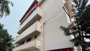 A multi-story building with balconies, a gated entrance, and potted plants. - Sri Mayapur Chandrodaya Guest House (Krishnanagar)