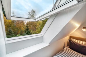 Una habitación con tragaluz, cama y vistas a árboles.