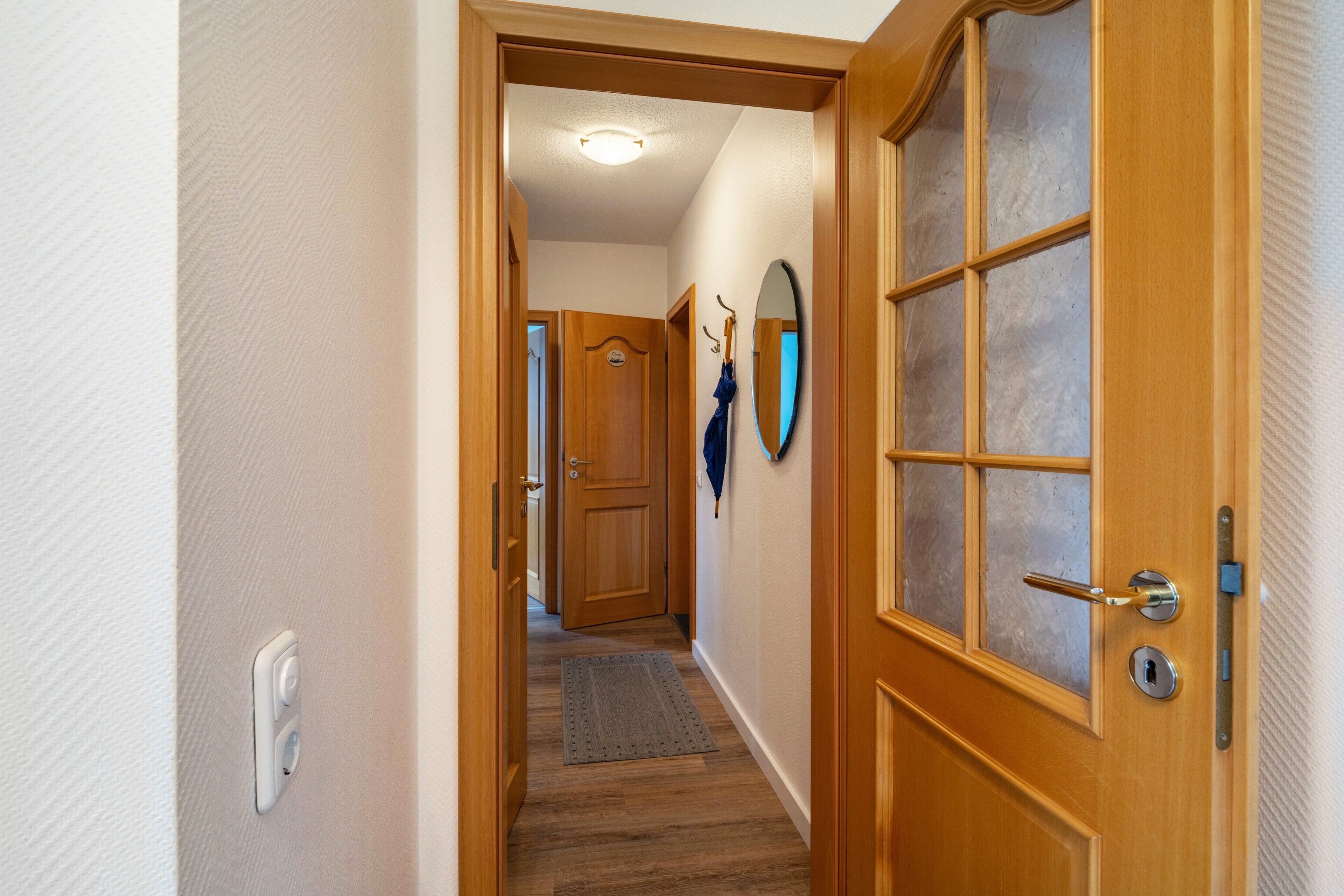 A hallway with a wooden door, a mirror, and a coat rack.
