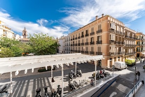 Une vue de rue avec des scooters garés, un fourgon blanc et un immeuble doté de balcons.