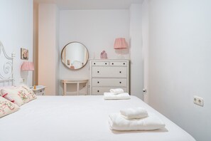 Une chambre à coucher avec un lit, une commode, un miroir, une lampe et une petite table.