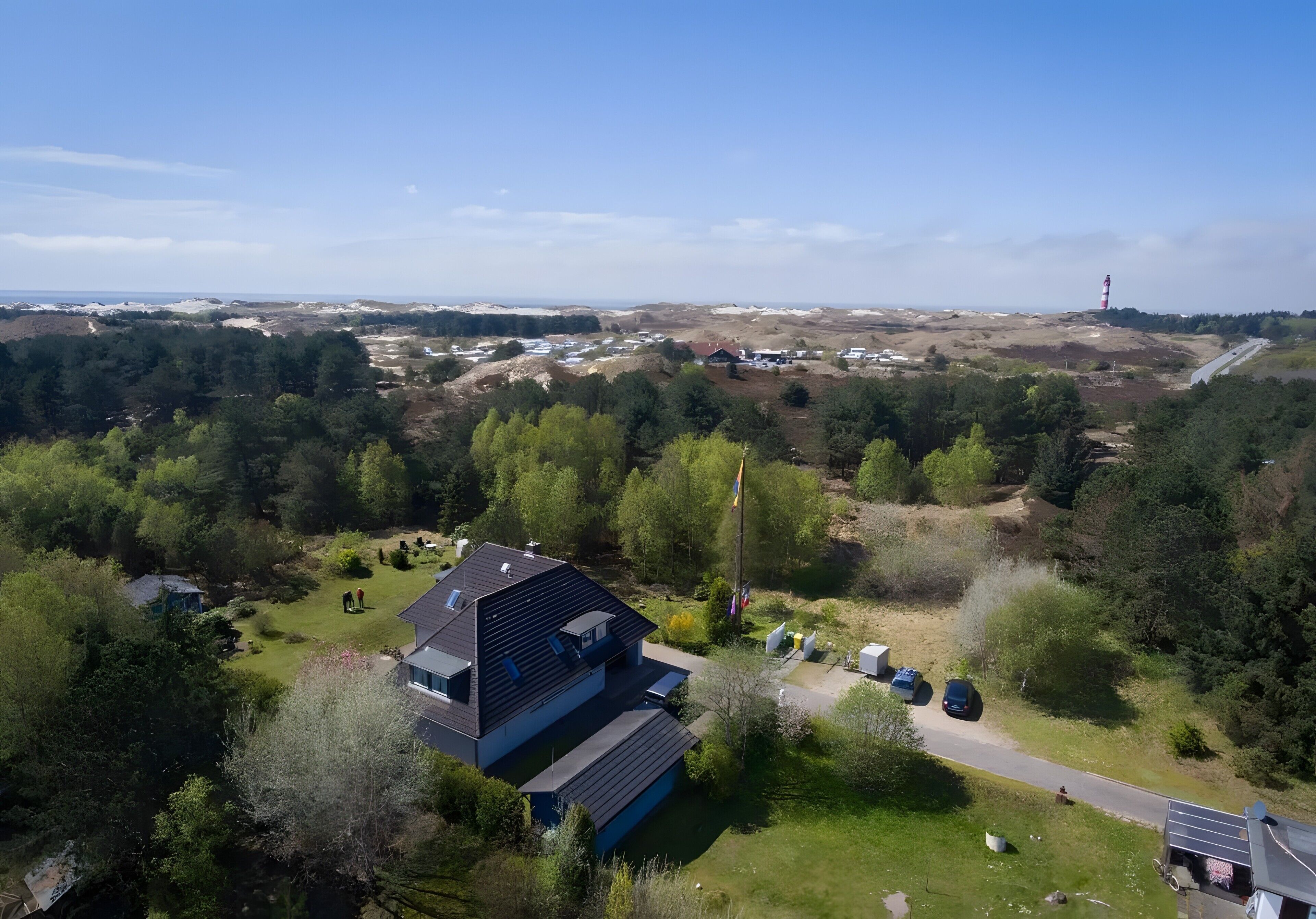 A modern house with a sloped roof, surrounded by greenery and a clear view of the landscape.