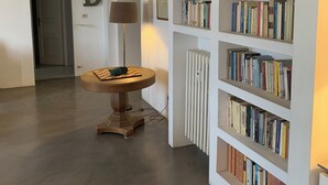 Ein Flur mit Bücherregal, einem runden Tisch mit Lampe und einer Tür mit Buchstaben.