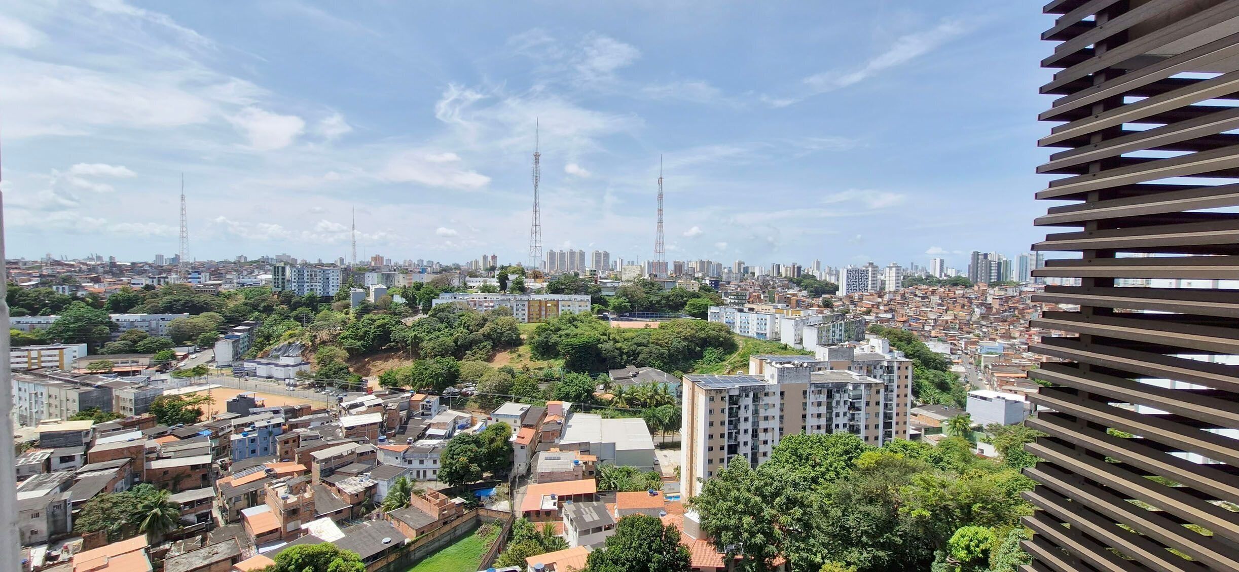 Paisagem urbana com uma mistura de edifícios altos e estruturas menores, céu claro e uma torre ao longe.
