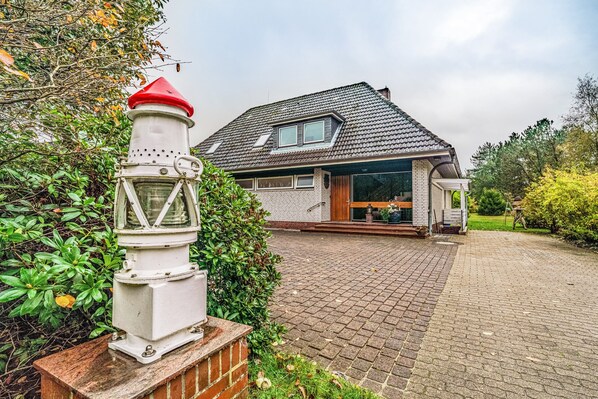 A house with a paved driveway, a white lighthouse-like structure, and a brick pathway.