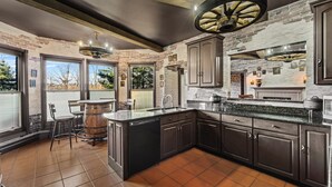 A modern kitchen with dark cabinetry, a large island, and a rustic brick wall.